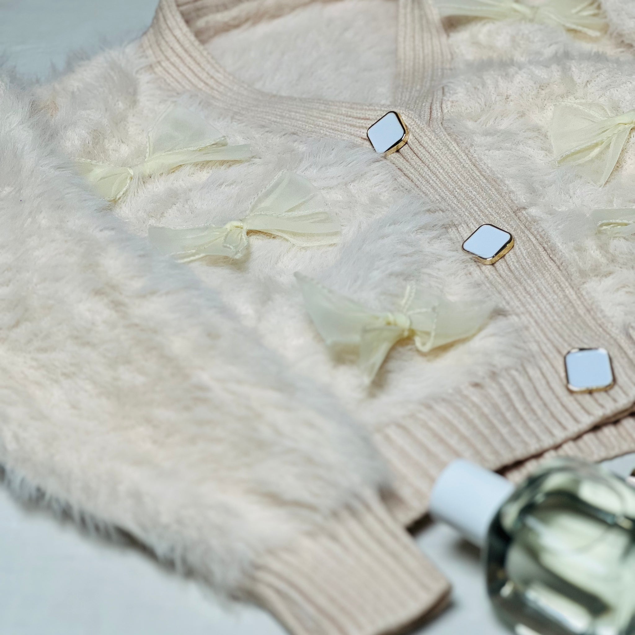 Beige fur woollen cardigan with charming bow accents for winter wear