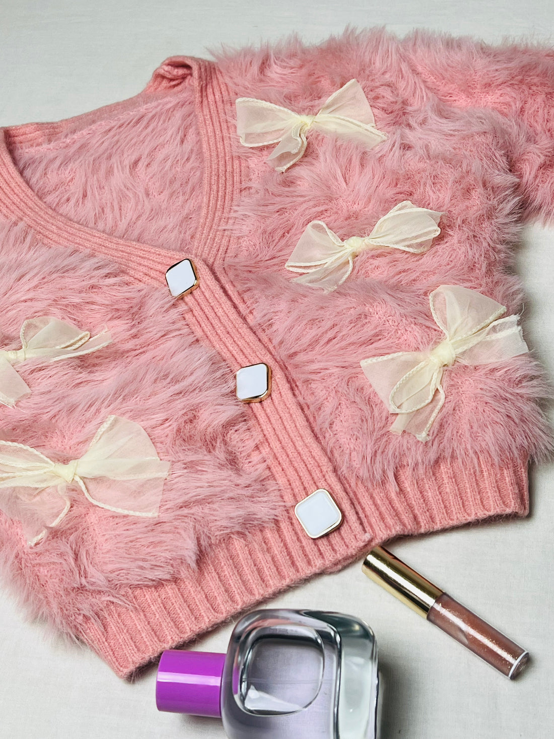 Peach woollen cardigan with charming bow accents for winter wear