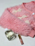 Fuzzy peach cardigan in soft wool with bow details for cozy winter styling.