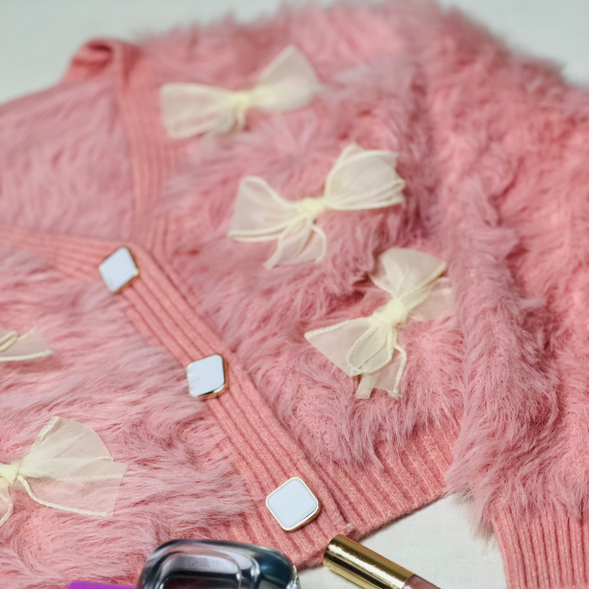 Peach woollen cardigan with charming bow accents for winter wear